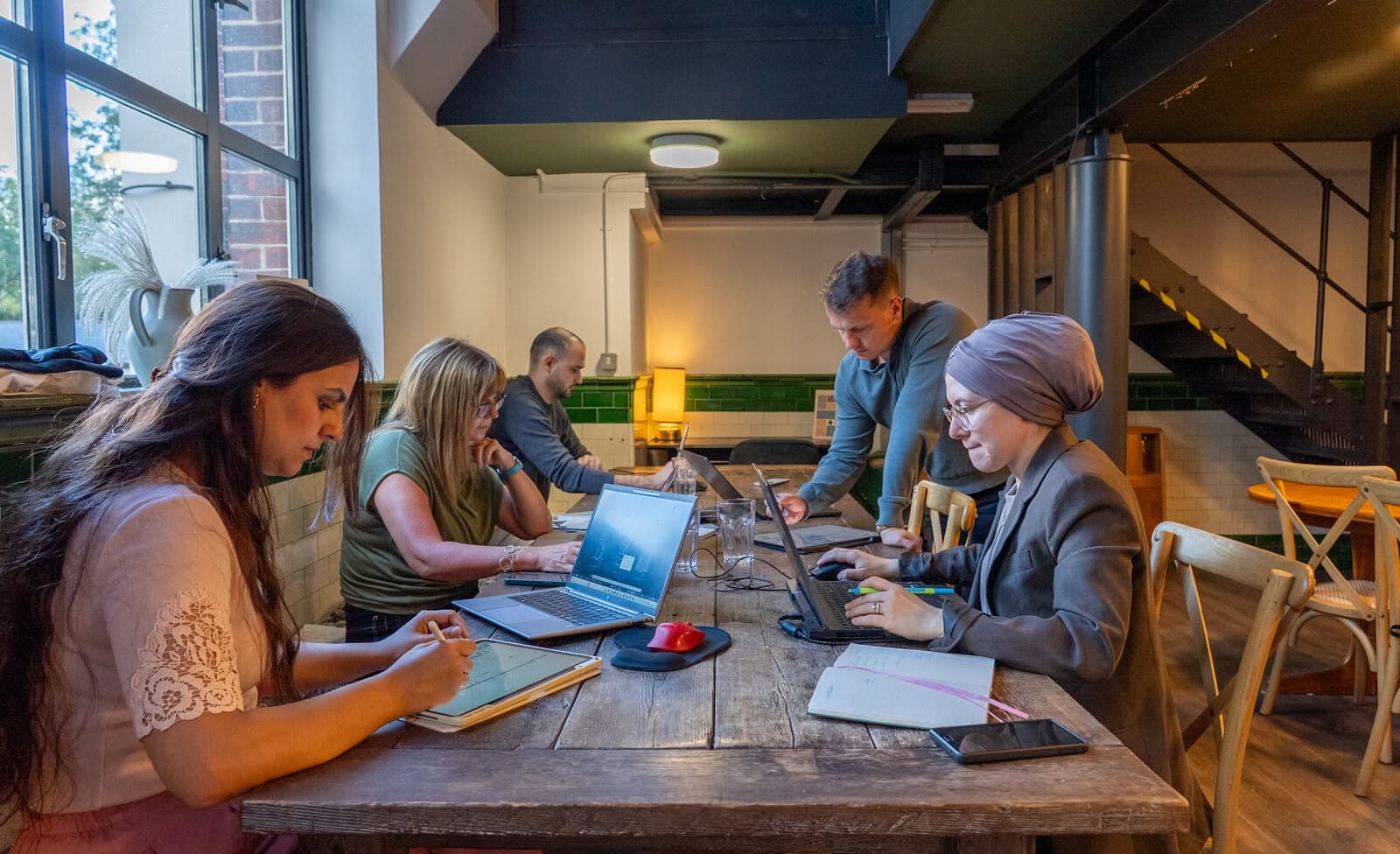 The Thistle Architecture team working together in the studio, reviewing plans on laptops and tablets